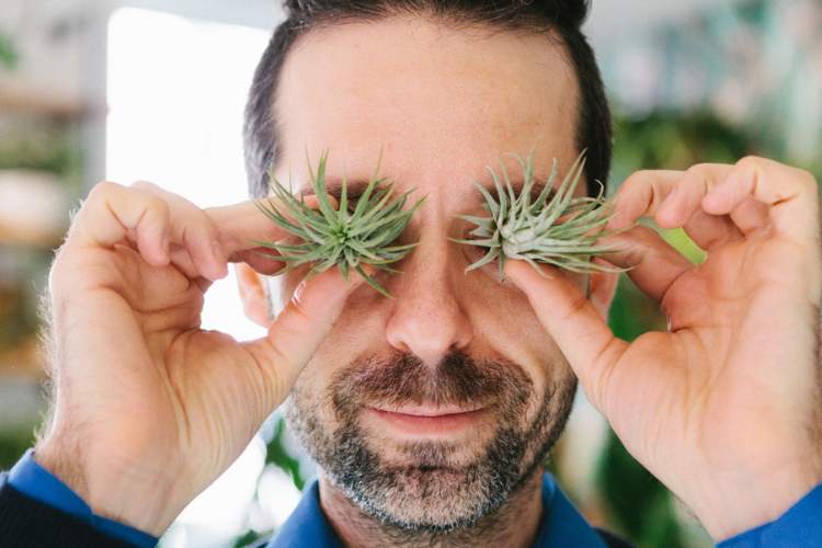 Vladan Nikolic (Mr. Houseplant) is holding with two small plants in front of his face